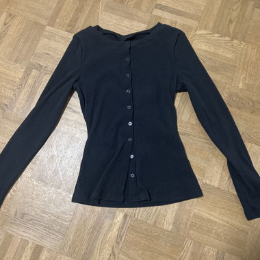 Haut noir à manches longues avec patte de boutonnage