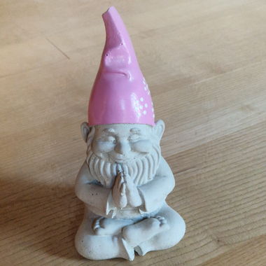 Gnomo da giardino che medita con cappello rosa