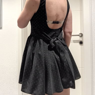 Kurzes schwarzes Kleid mit Pailletten und Schleife in der Taille