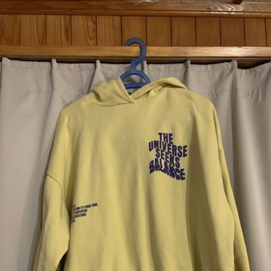 Hellgelber Pulli, Violette Aufschrift
