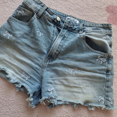 Shorts in denim coquette con ricamo di fiocchi