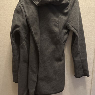 Grauer Mantel mit asymmetrischem Schnitt