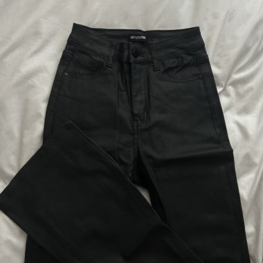 Pantaloni a zampa con denim nero effetto coating e taglio al fondo