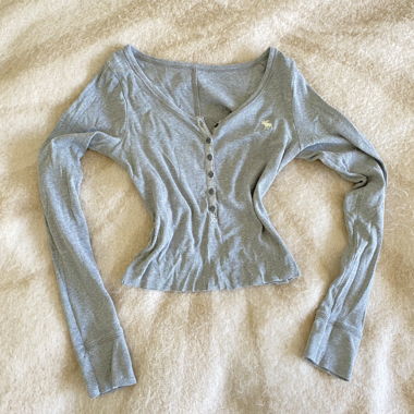 Top grigio a maniche lunghe con patta con bottoni