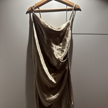 Miniabito in raso dorato con spalline sottili regolabili e scollo drappeggiato.