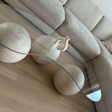 Tavolino in vetro scultoreo con piedi in travertino