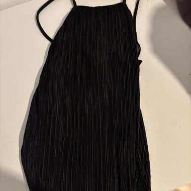 Top nero plissettato con sottili spalline a spaghetti e schiena incrociata