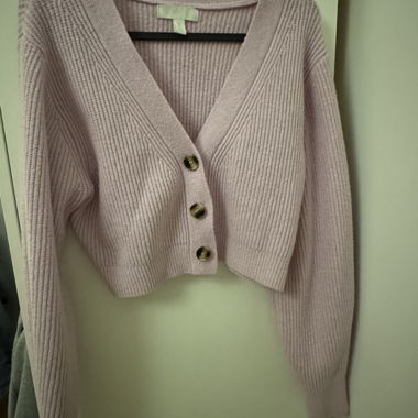 Cardigan corto in maglia a coste rosa chiaro, maniche lunghe e scollo a V.