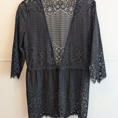 Short kimono in black openwork lace with three-quarter sleeves and scalloped edge. Open-front style with a tie belt at the waist. Lightweight, sheer fabric, suitable as a cover-up or over tops and dresses. In good condition, no visible defects.