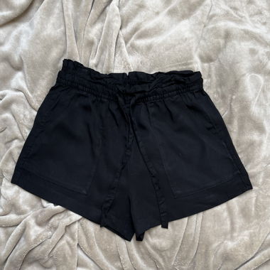 Schwarze, weite High-Waist-Shorts, in der Taille zu schnüren. Zwei Vordertaschen, fließendes Material.