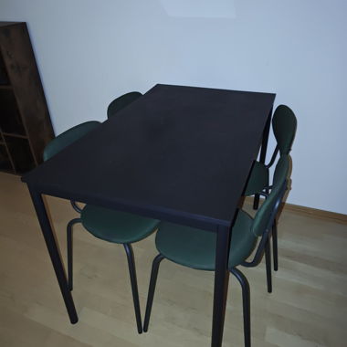 Black dining table with 4 green chairs